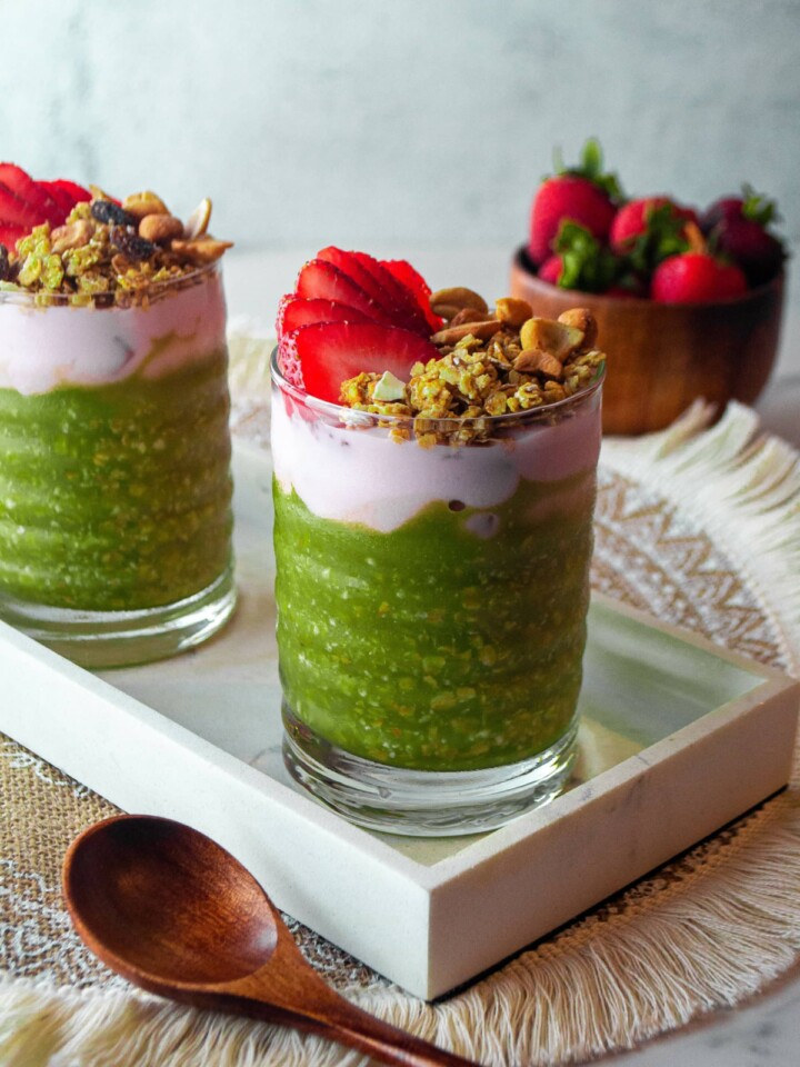green matcha overnight oats with nuts and strawberry in a glass