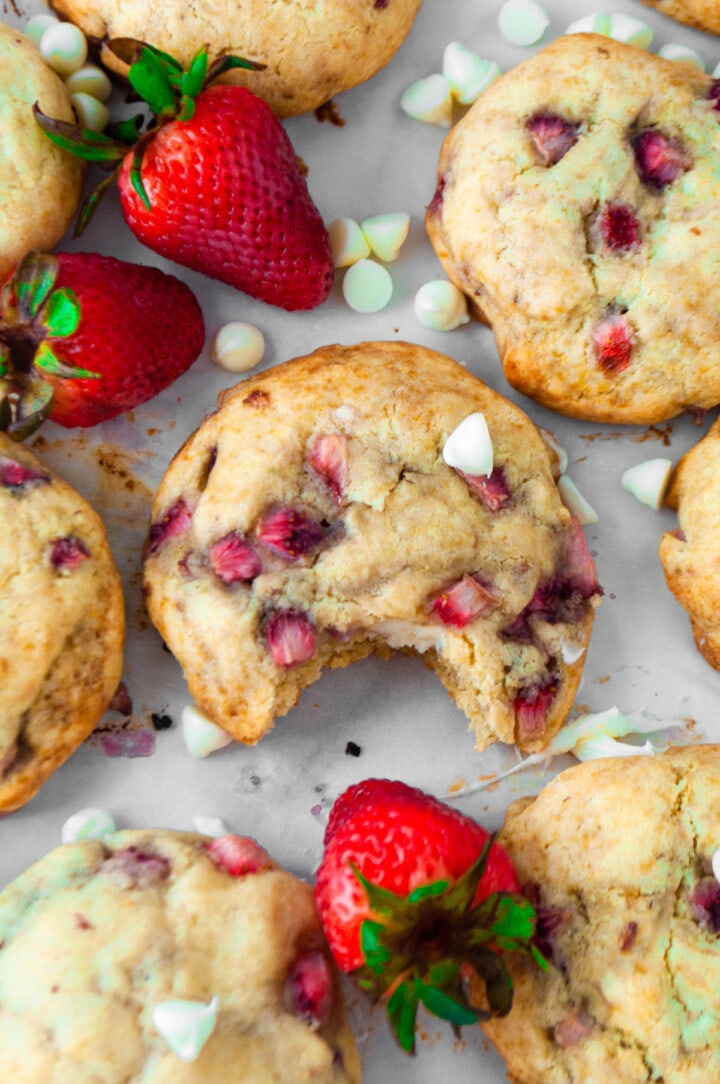 a bite in a cookie surrounded with strawberries
